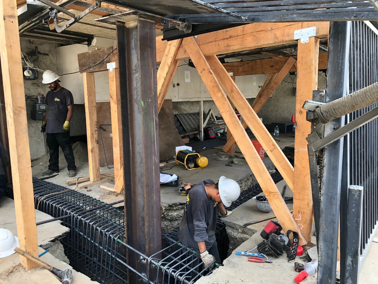 New steel column set on a reinforcing-steel footing cage, forming the grade-beam foundation of a soft-story retrofit.