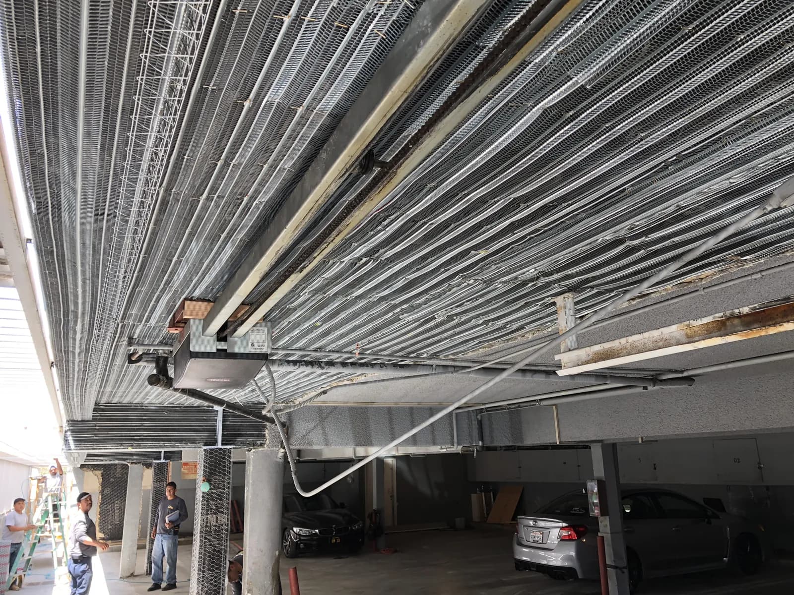 Metal lath installed across the ceiling of a parking level in preparation for a plaster shear wall on a soft-story retrofit.