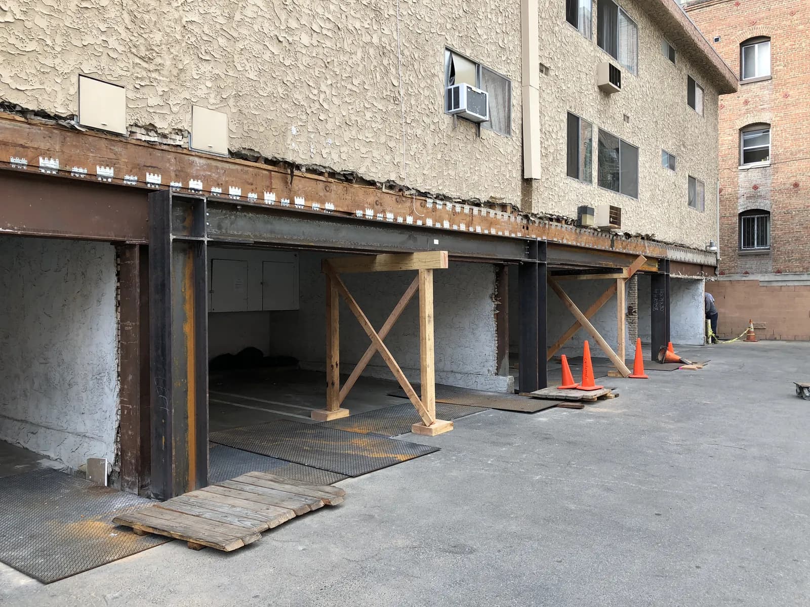 Completed steel moment frame with temporary shoring, reinforcing the soft-story ground floor of a stucco multifamily building.